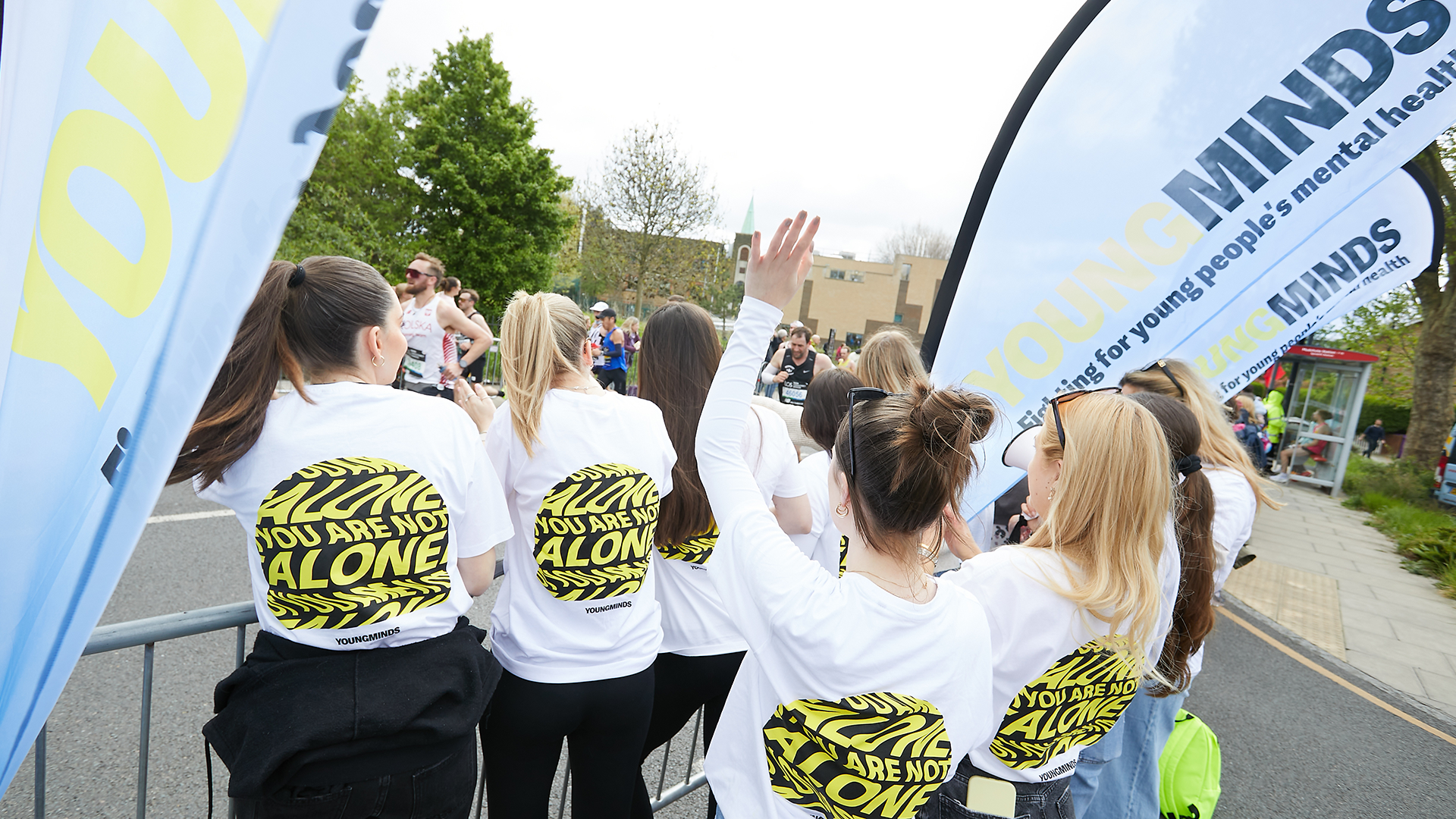YoungMinds staff cheering marathon runners on from the side line in YoungMinds t-shirts and with YoungMinds banners.