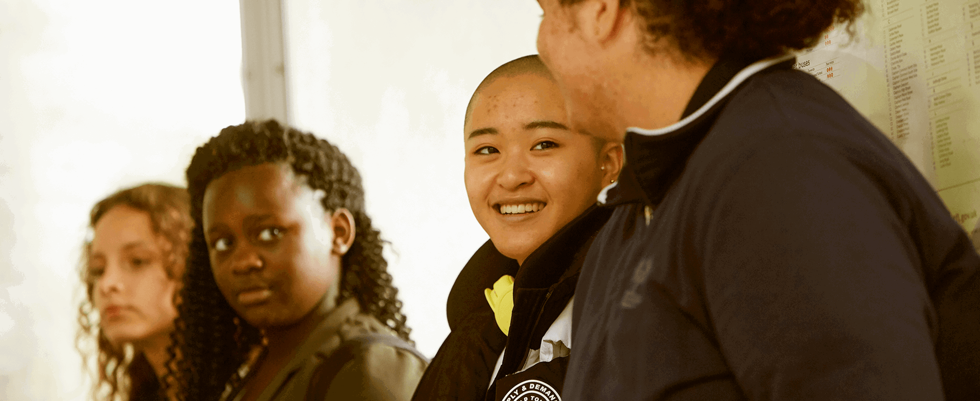 Four young people sitting together in a corridor.