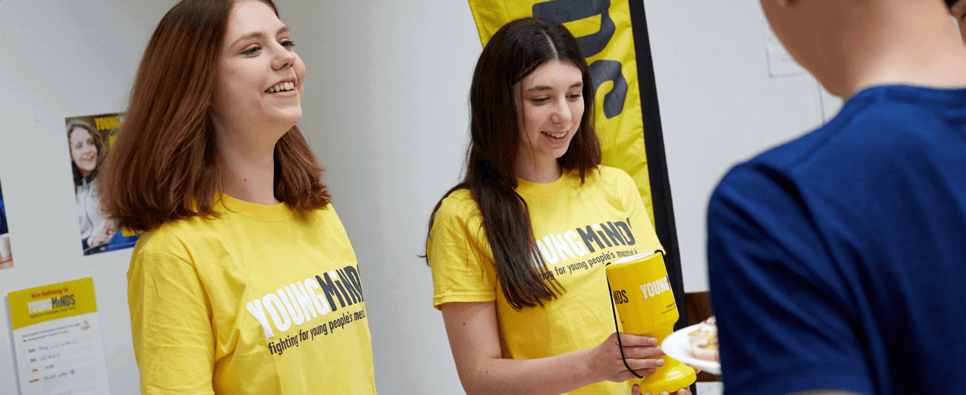two fundraising volunteers wearing youngminds shirt smiling while giving out fundraising materials
