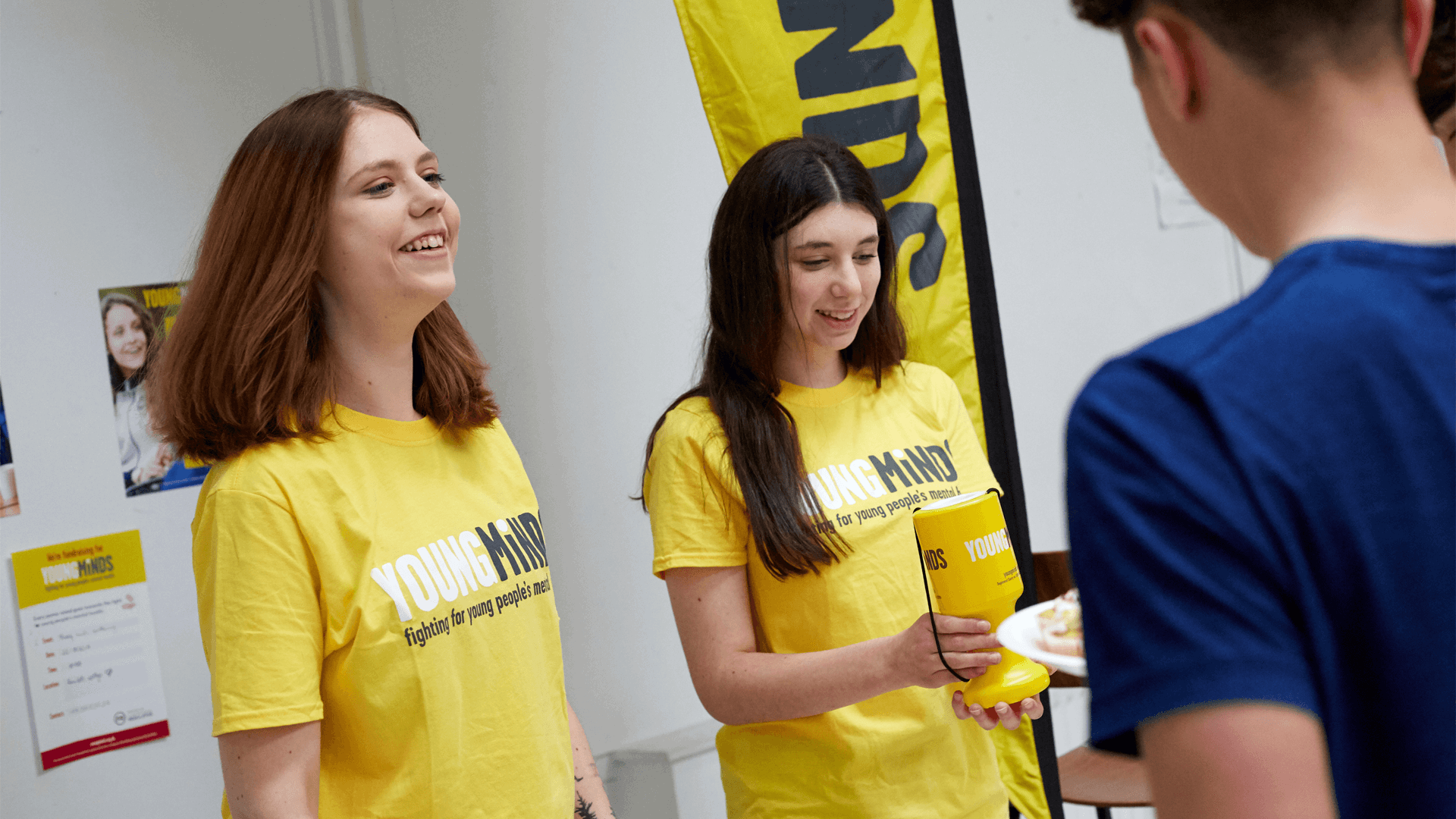 two fundraising volunteers wearing youngminds shirt smiling while giving out fundraising materials