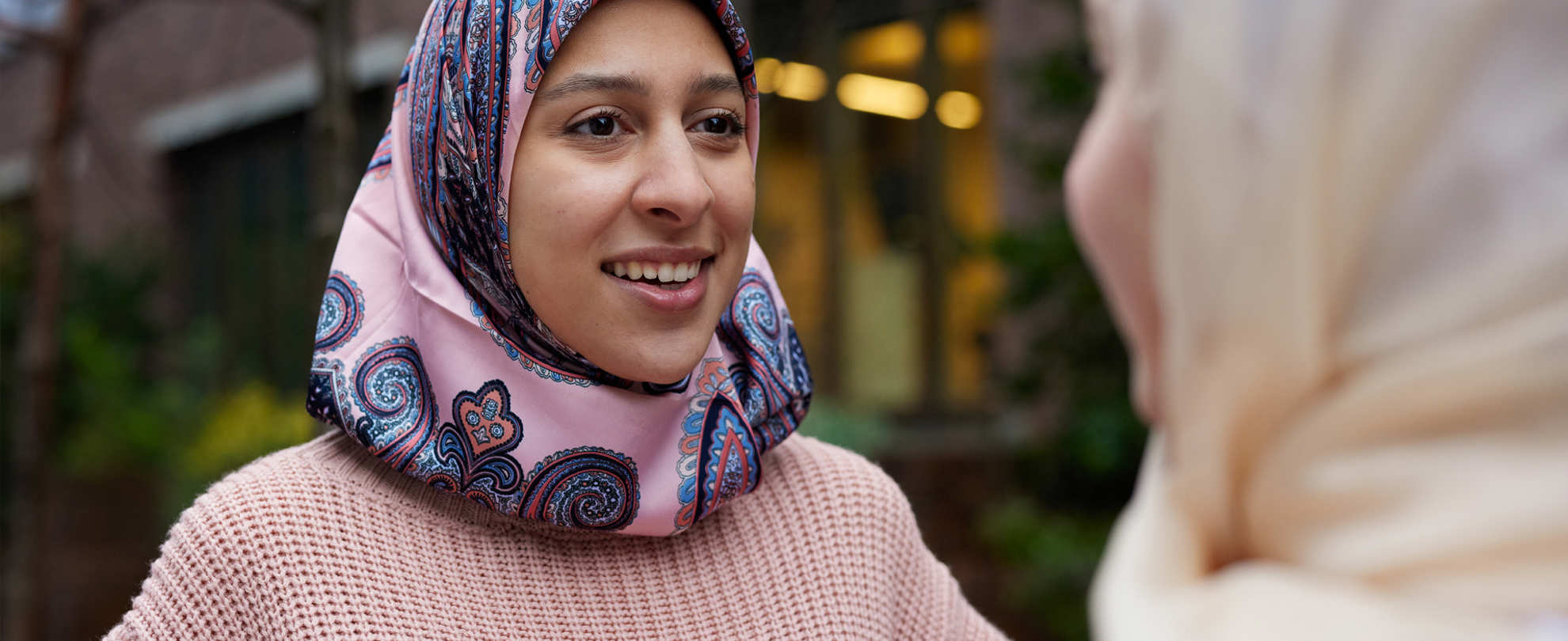 Two young Muslim women in headscarves talking.