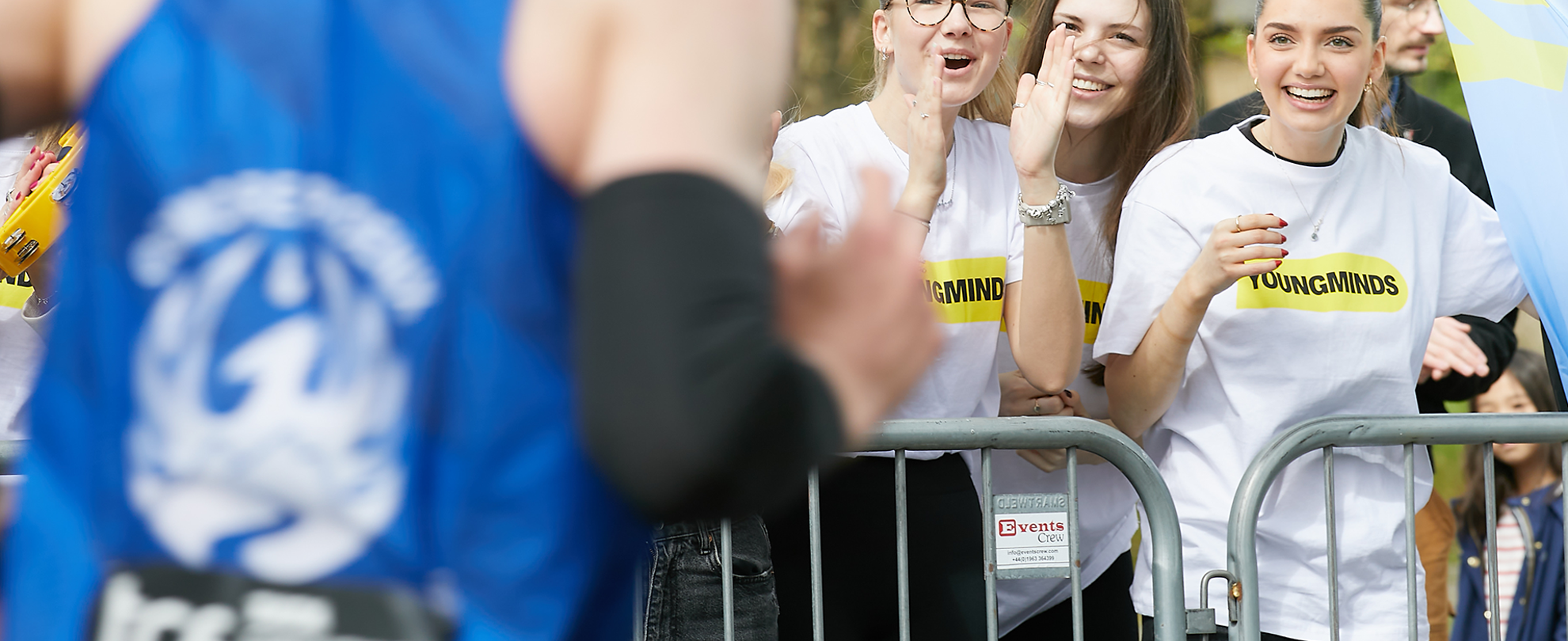 A YoungMinds marathon runner being supported by YoungMinds staff on the side line.
