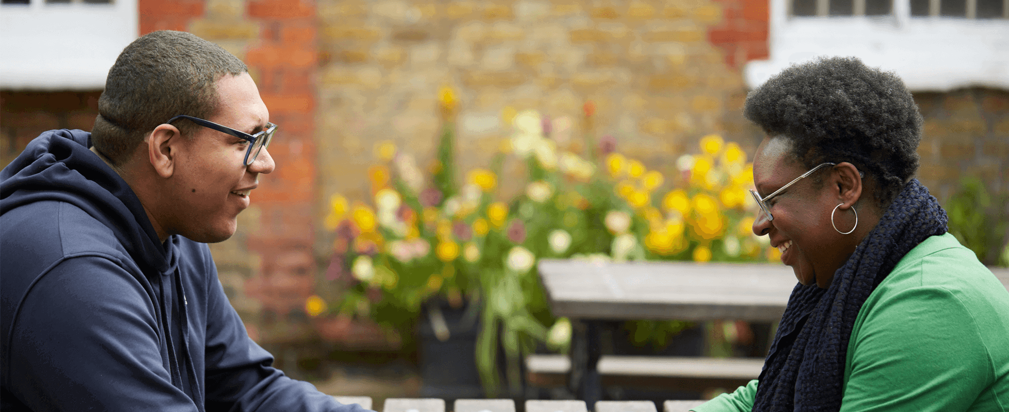 A mother and son hold hands and bond at an outside table