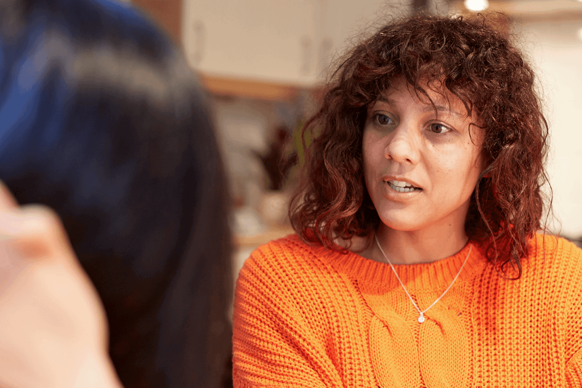 A girl wearing a bright orange jumper in deep conversation