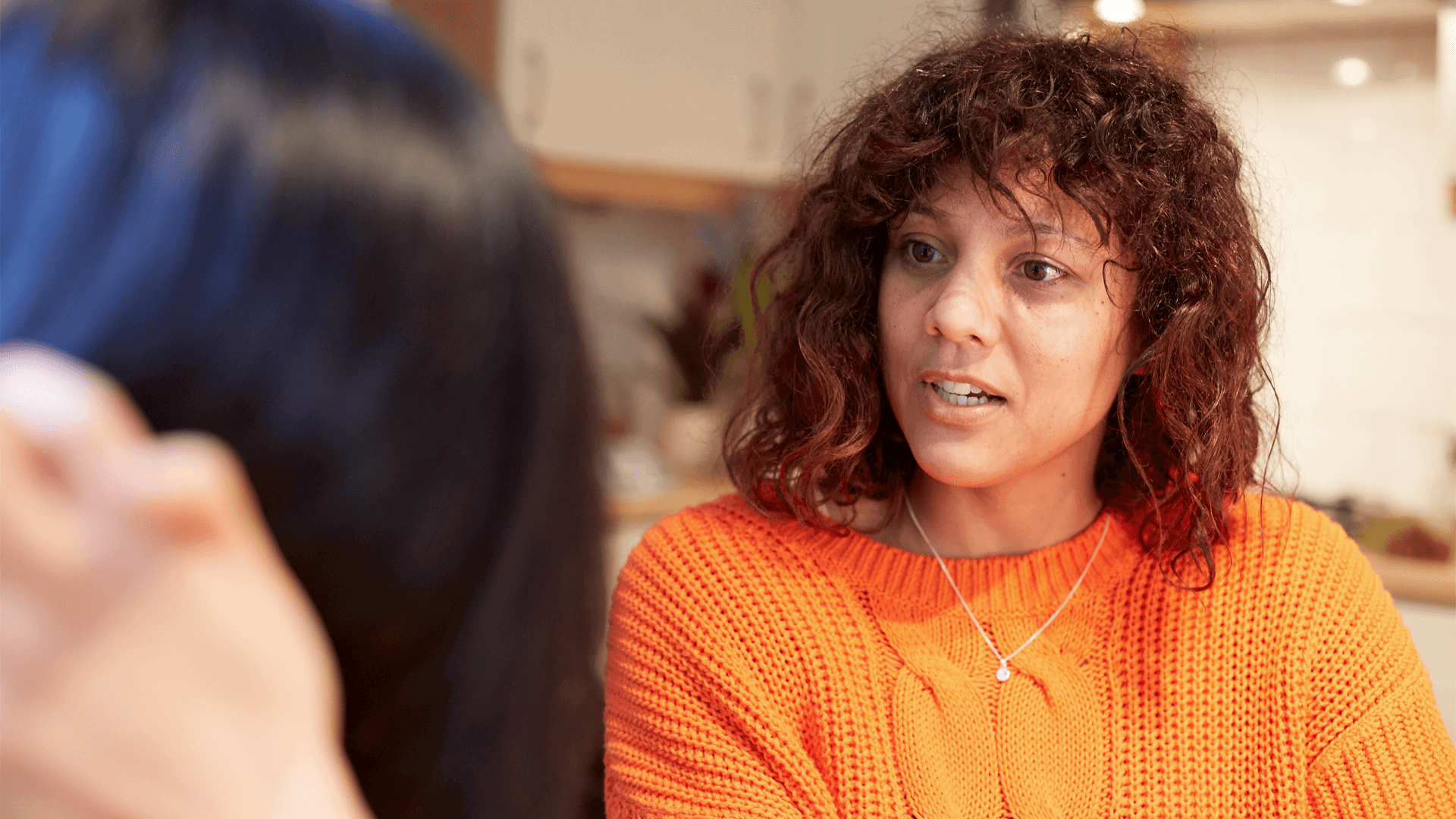 A girl wearing a bright orange jumper in deep conversation